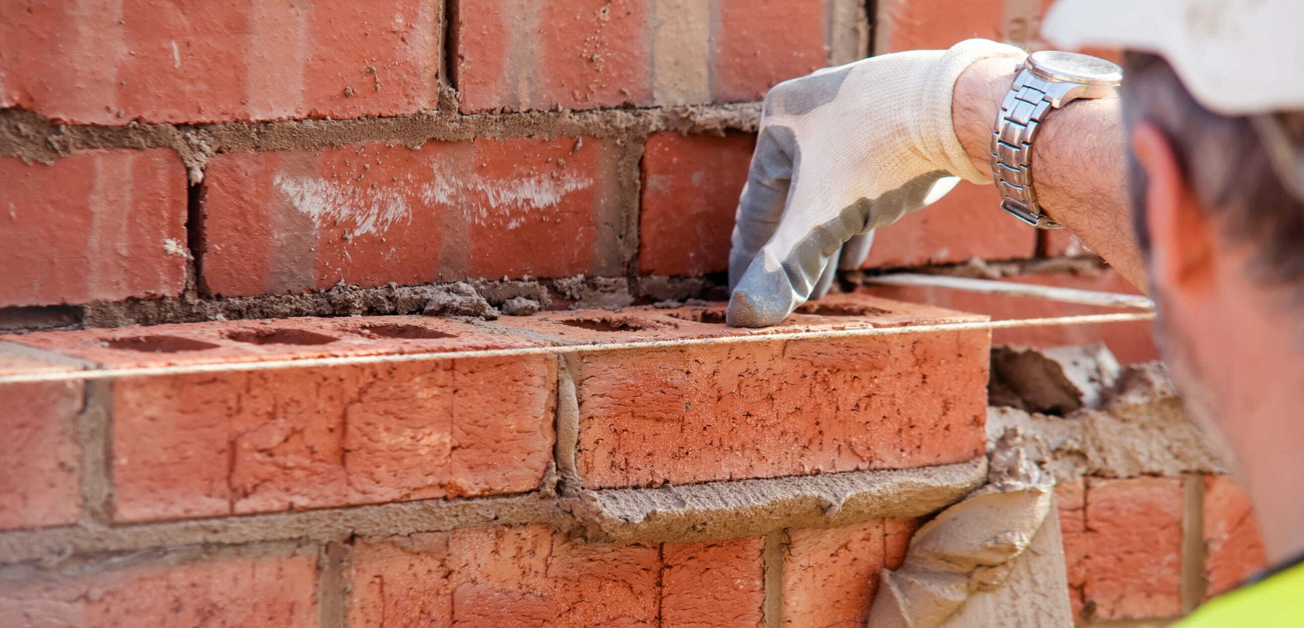 Bricklayer placing brick onto wall