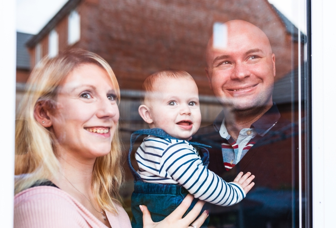 Happy family with baby looking through window
