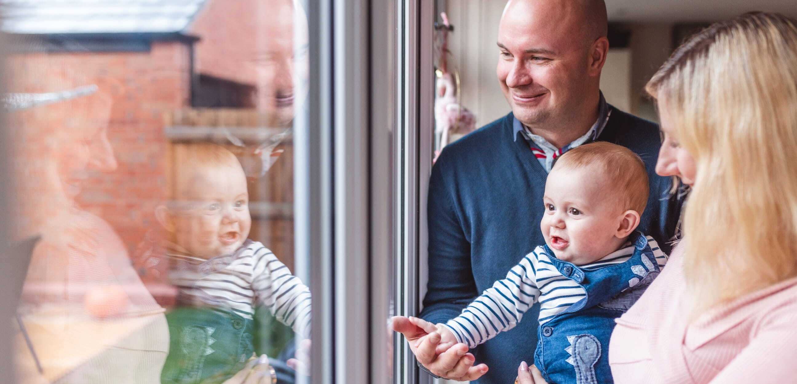 Happy family with baby looking out of window